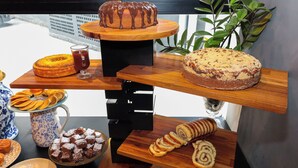 A variety of baked goods displayed on wooden stands, including a bundt cake, a loaf of bread, and pastries. - H4 Hotel Opera Jardins (São Paulo)