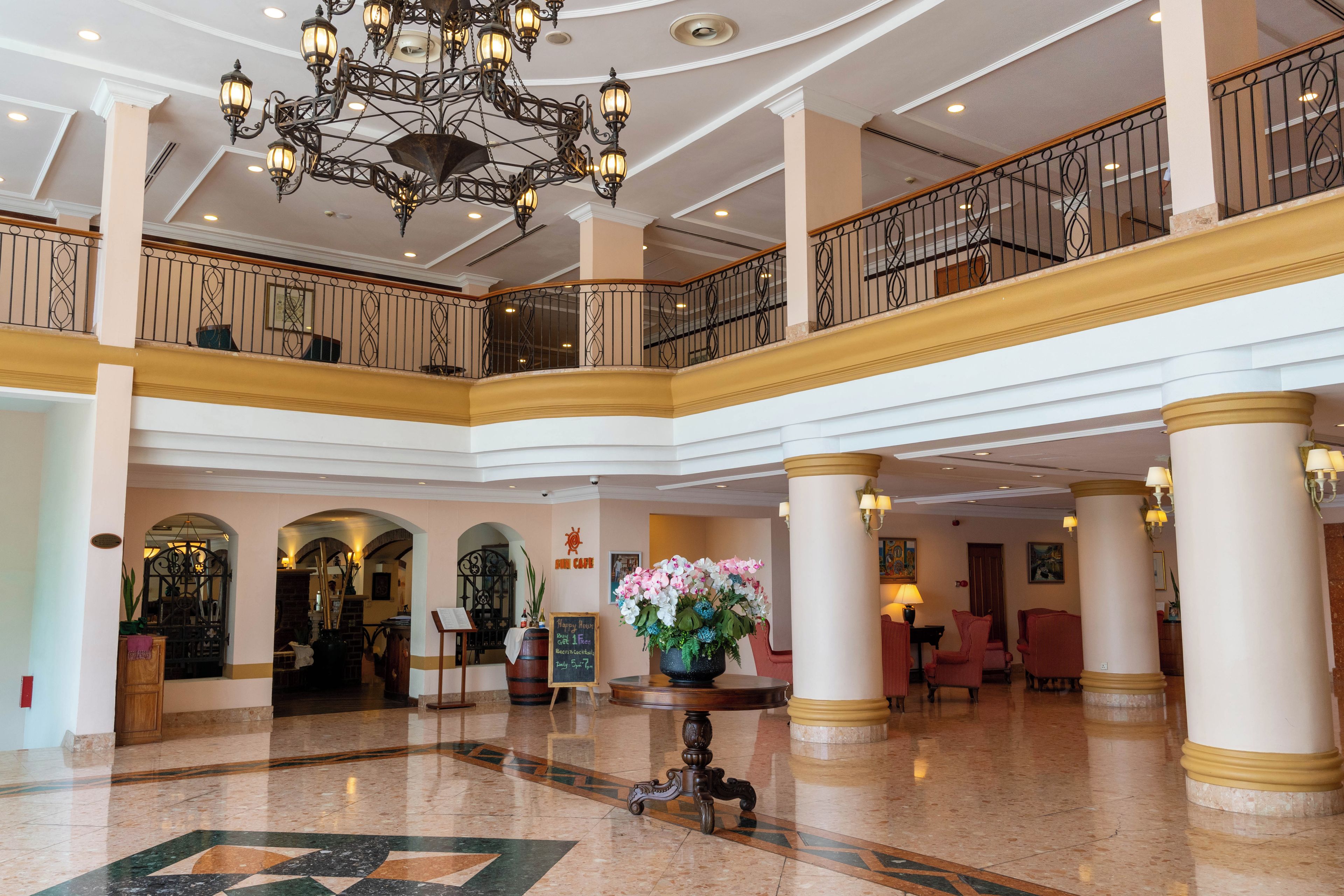 A spacious lobby with a grand chandelier, a coffee shop, and a reception desk.