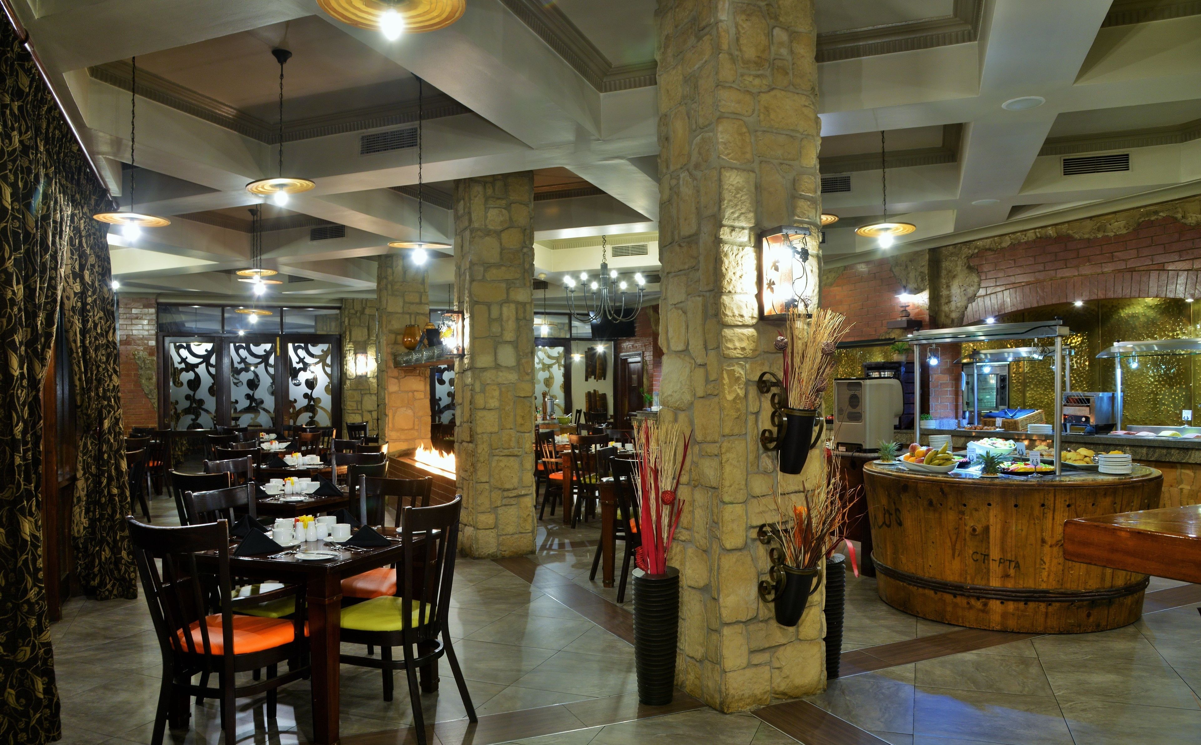A restaurant with stone pillars, wooden tables, and a buffet area.