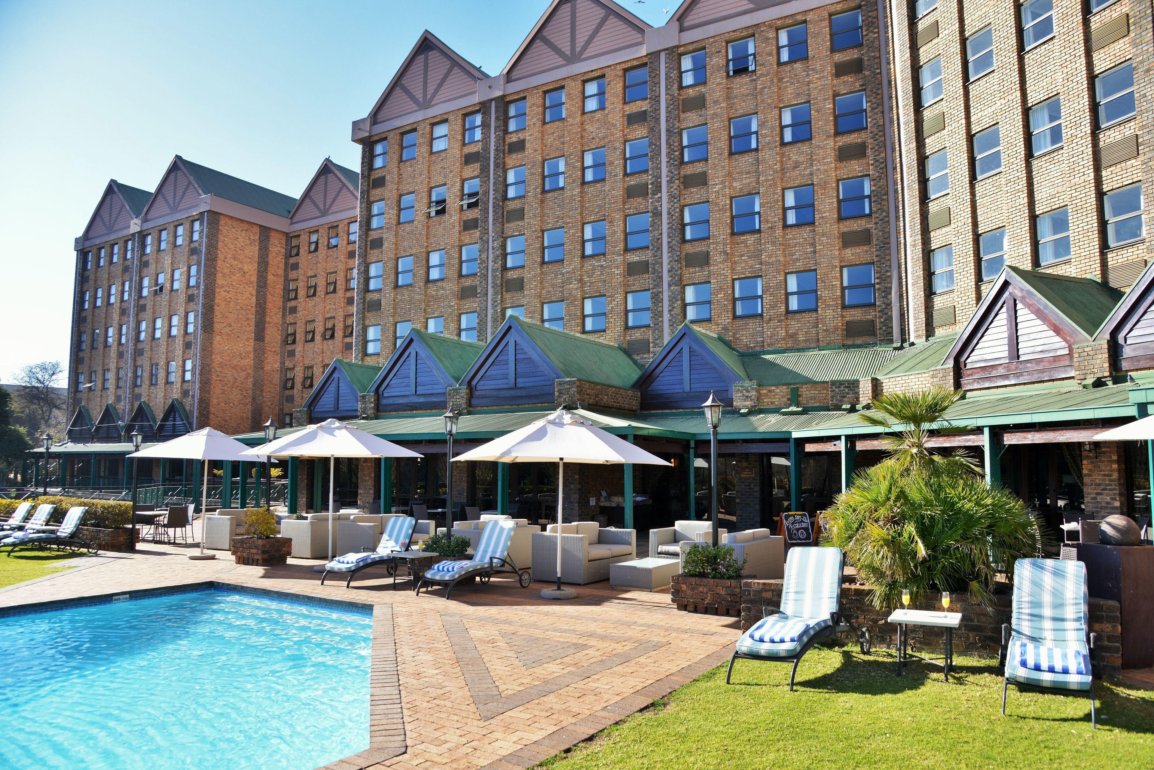Ein Hotel mit Schwimmbad, Sitzgelegenheiten im Freien und einem großen Backsteinhaus mit vielen Fenstern.