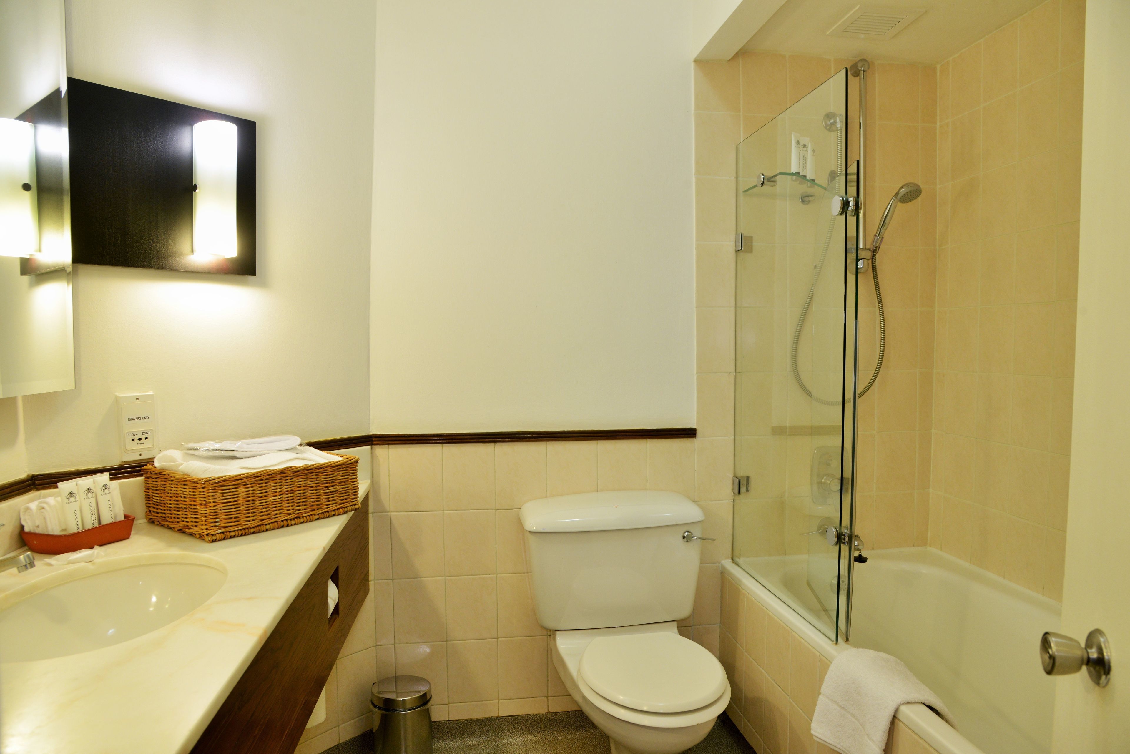 Un baño con lavamanos, inodoro y ducha con mampara de vidrio.