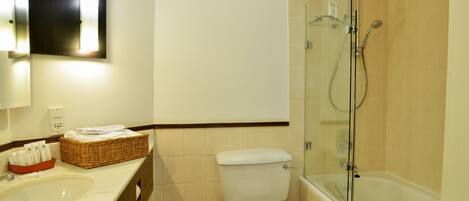 Un baño con lavamanos, inodoro y ducha con mampara de vidrio.