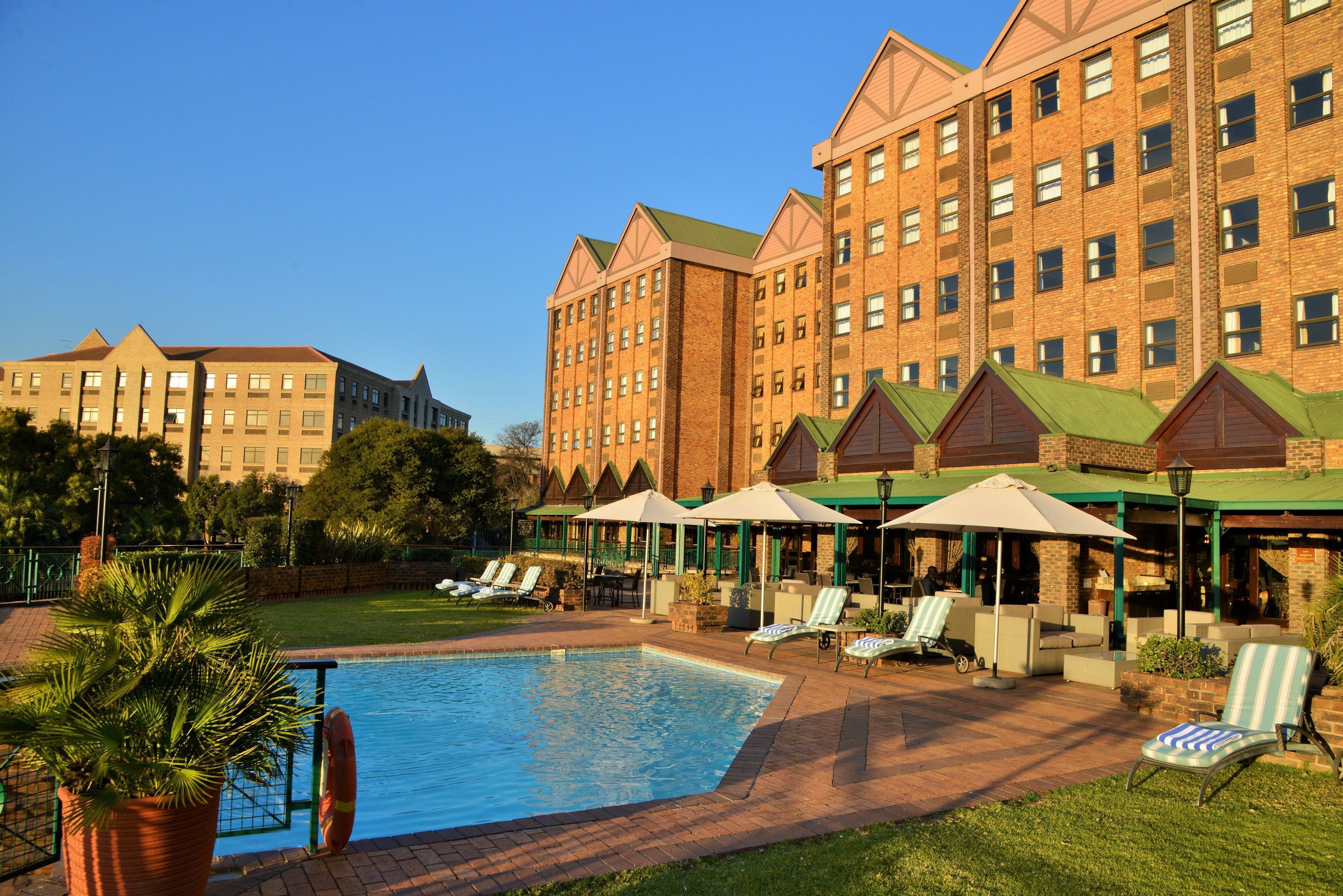Un hotel con piscina, mobiliario exterior y fachada de ladrillo.