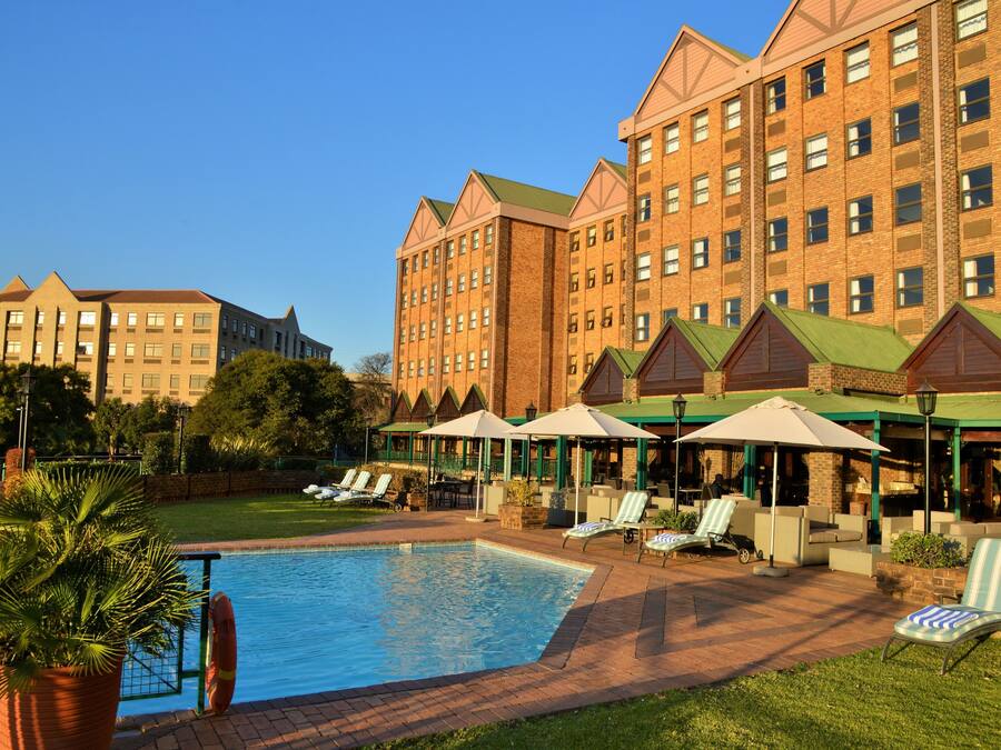 Un hotel con piscina, mobiliario exterior y fachada de ladrillo.