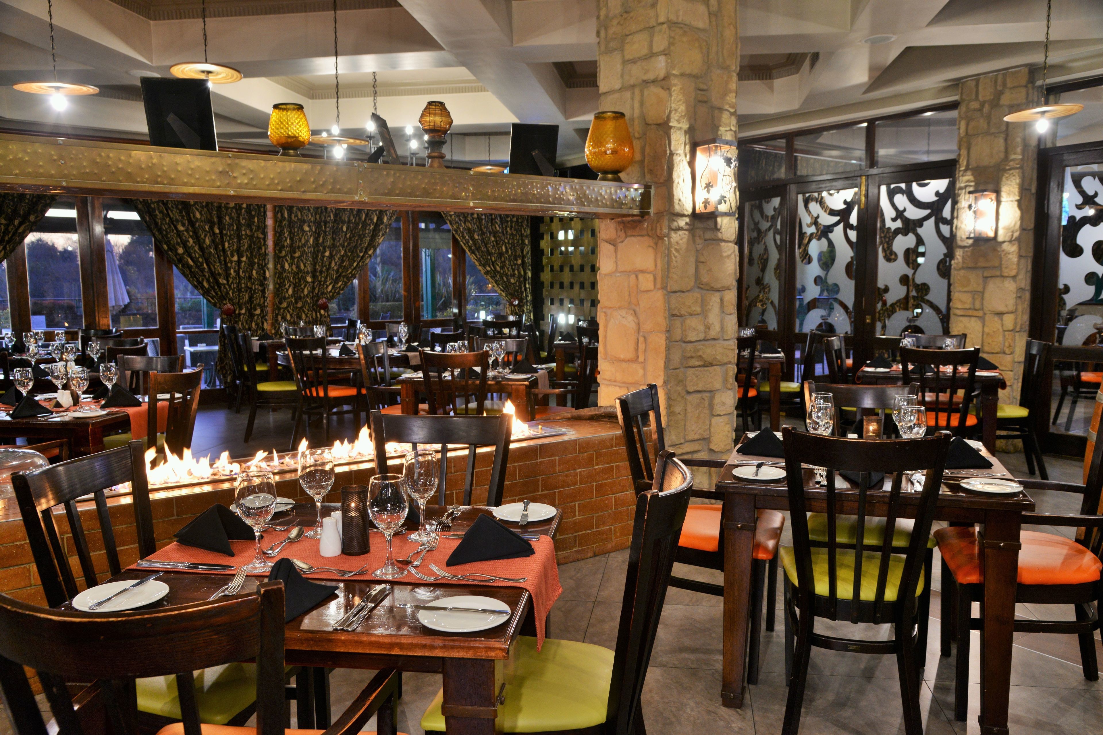 Un restaurant doté de nombreuses tables, de chaises et d’un foyer central.