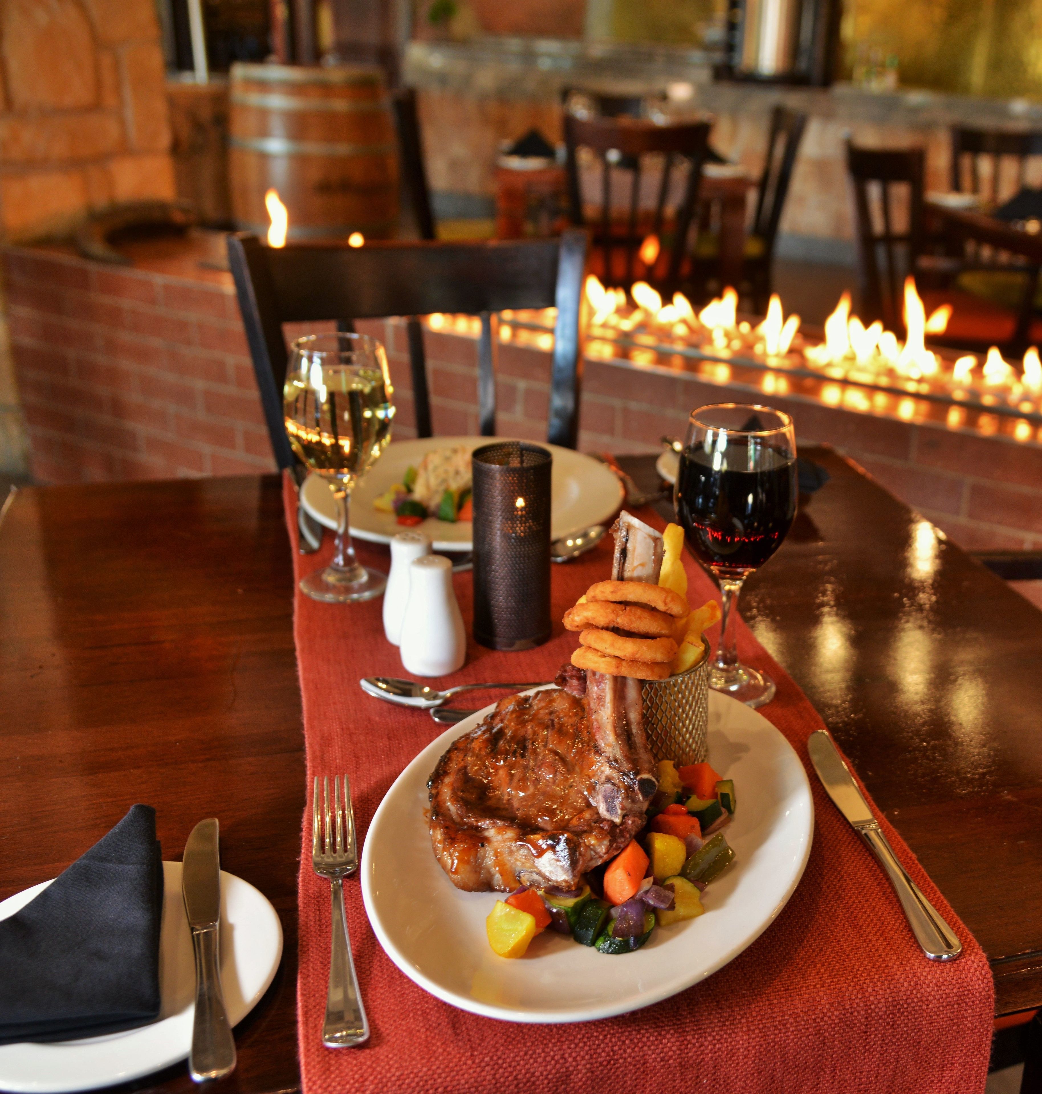Une table à manger avec une assiette de nourriture, un verre de vin blanc et un verre de vin rouge.