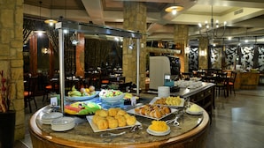 Montaje de bufé con diferentes opciones de comida, como frutas, pasteles y una estación de café.