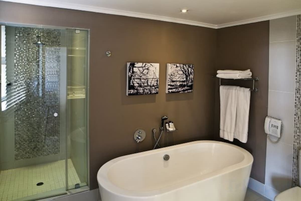 A bathroom with a glass-enclosed shower, a freestanding bathtub, and two wall-mounted towel racks.