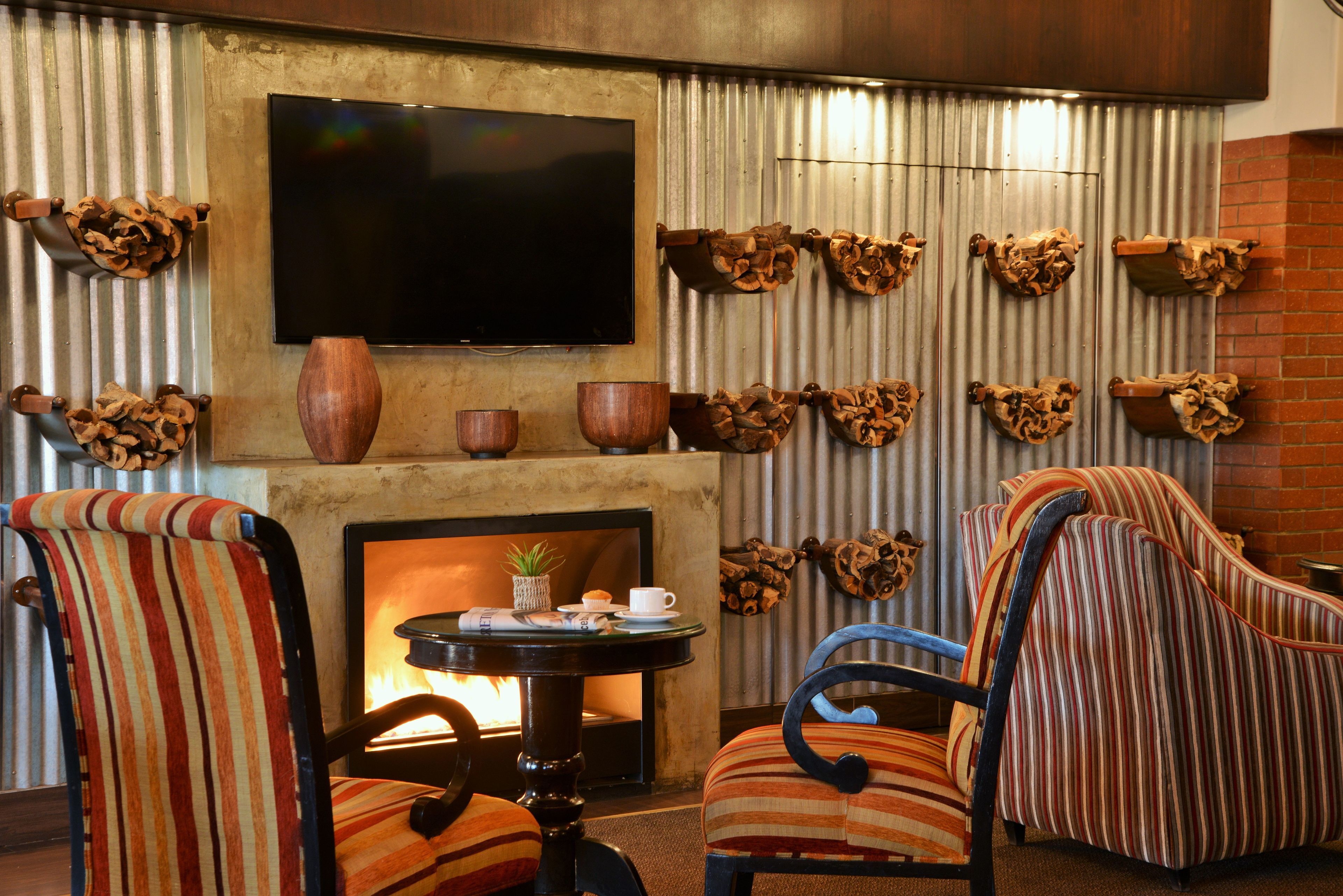 A cozy lounge area with striped chairs, a fireplace, a flat-screen TV, and decorative wooden elements.