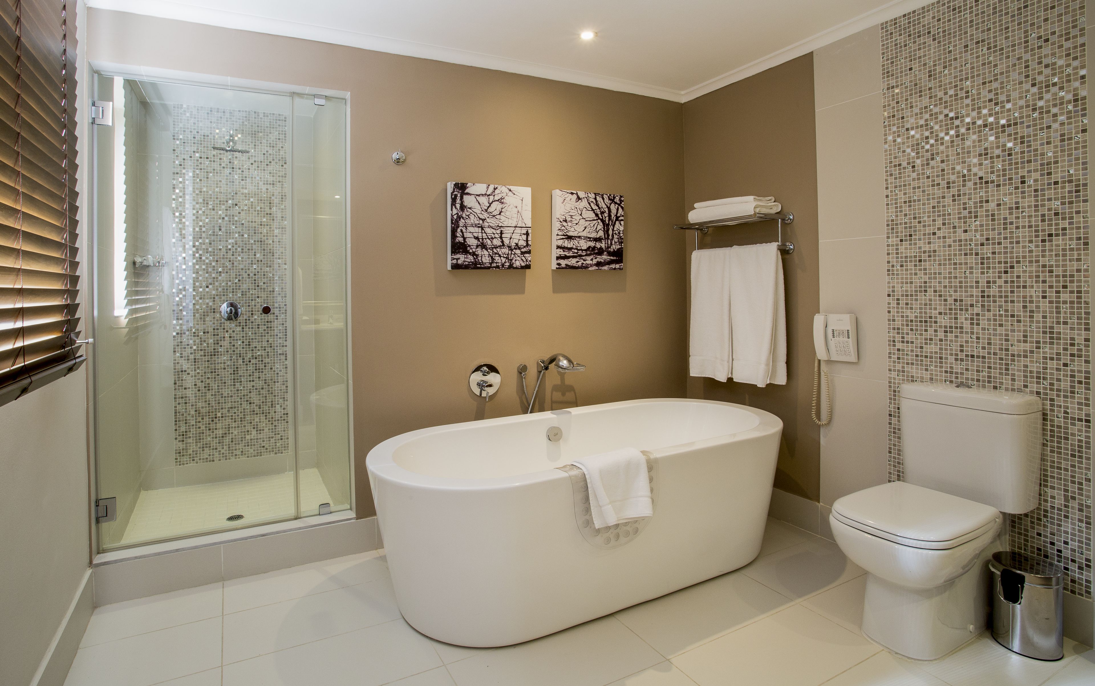 A modern bathroom with a glass-enclosed shower, a freestanding bathtub, and a toilet.
