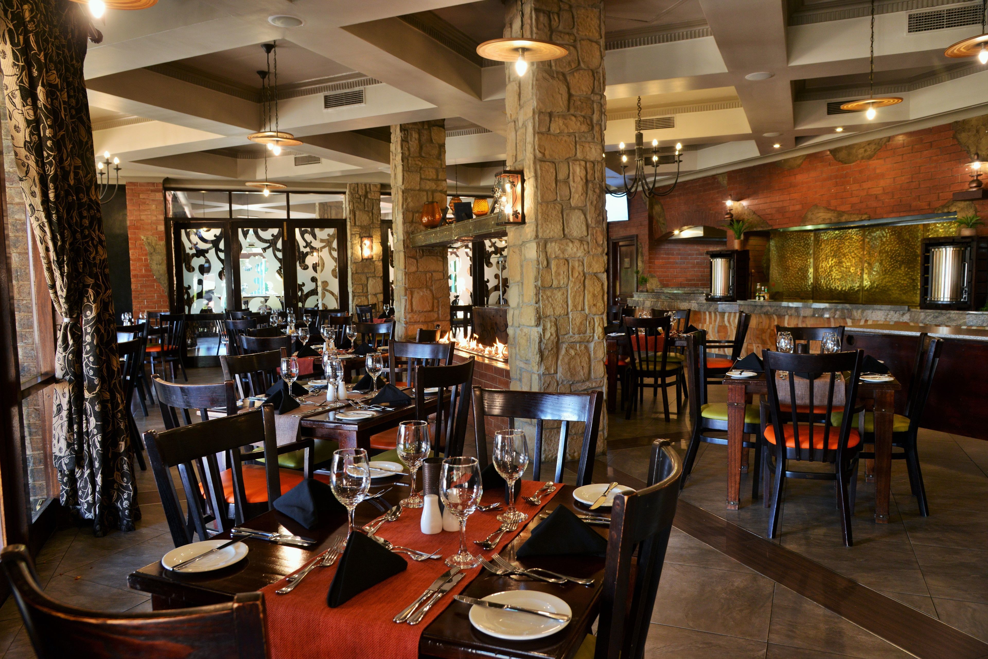 A restaurant with stone pillars, wooden tables, and chairs.