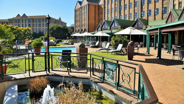 Un hotel con piscina, sillas de descanso y una fuente.