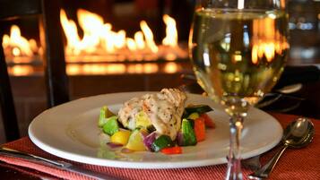 Ein Teller mit Essen und ein Glas Weißwein auf einer Tischplatte mit roter Unterlage.