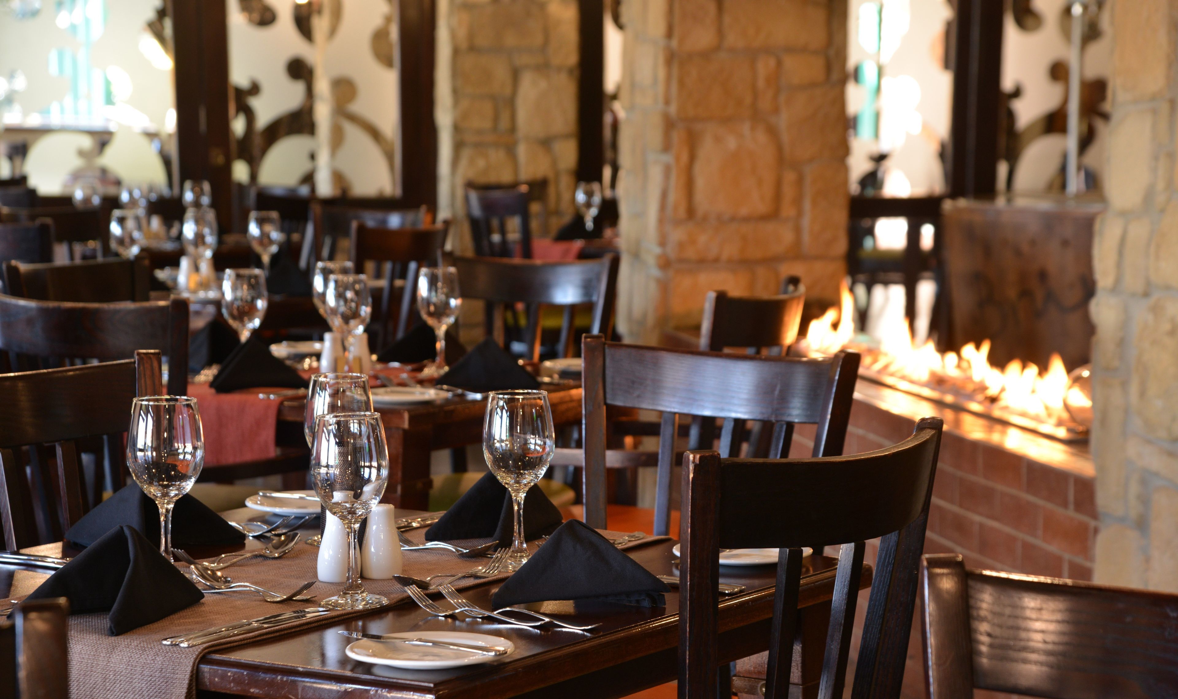 Interior de restaurante con mesas y sillas de madera, y una chimenea de ladrillo.