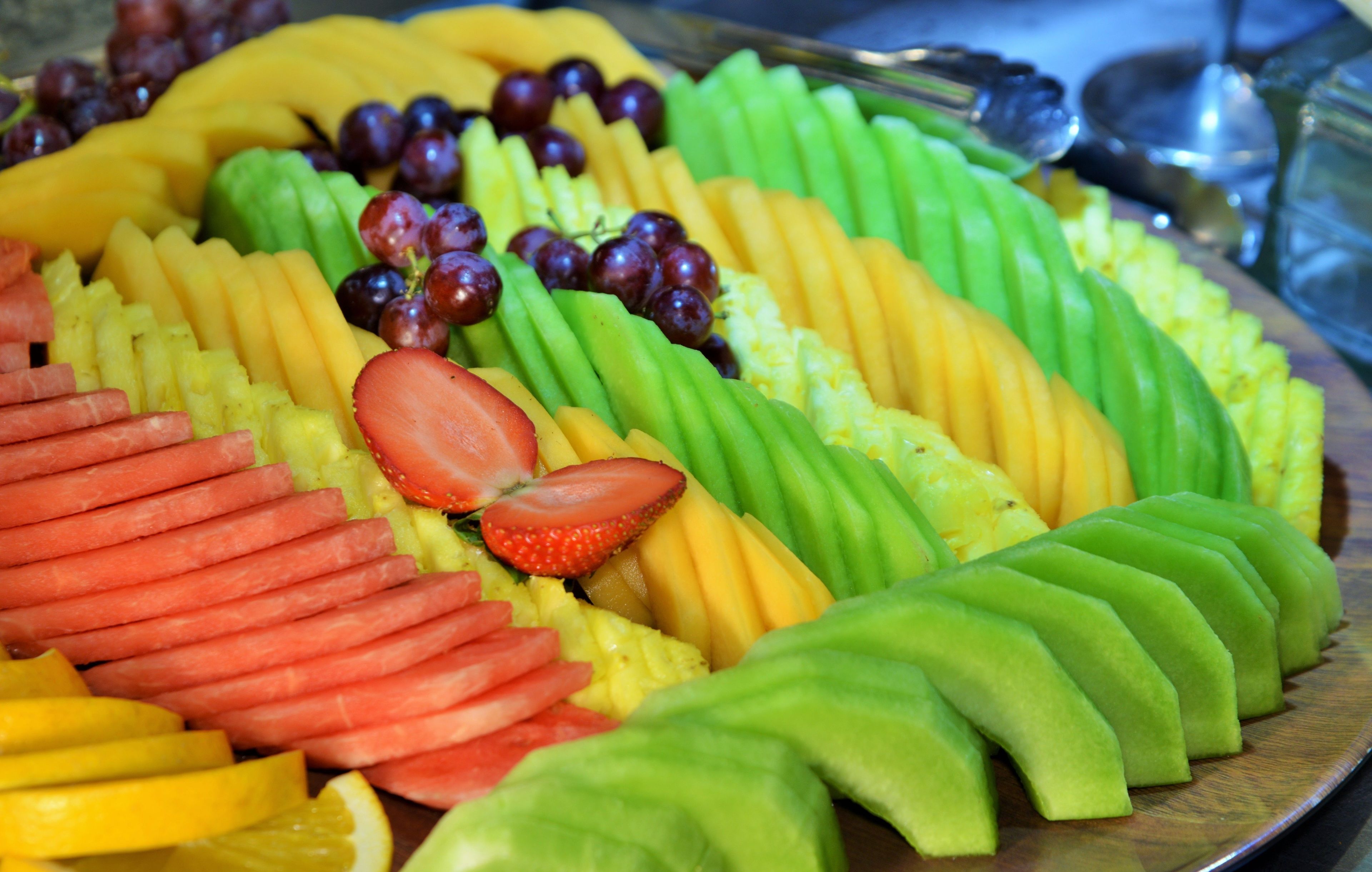 A fruit platter with various sliced fruits and grapes.