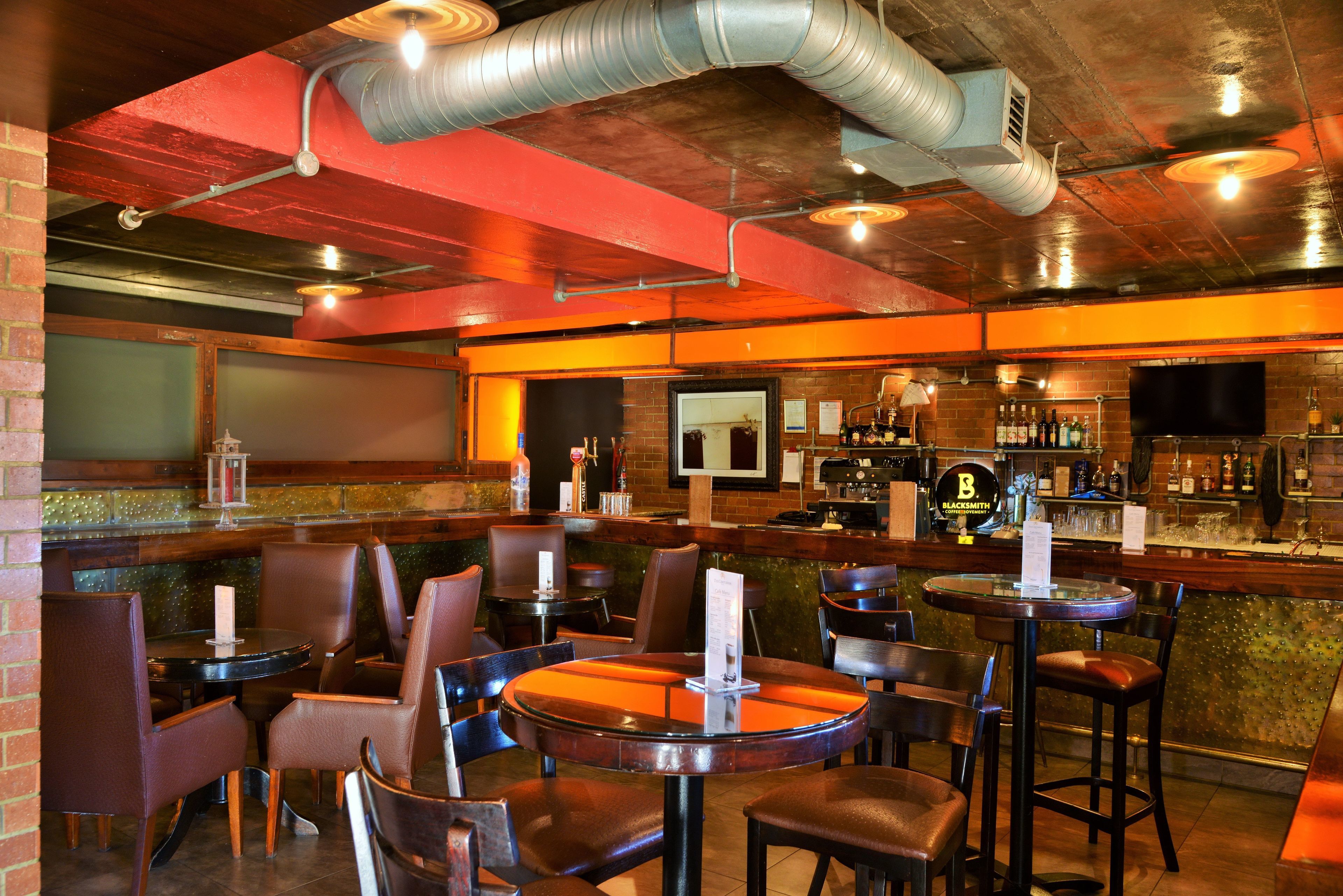 Un espace bar avec des tables et des chaises, un comptoir avec un téléviseur et un mur en briques.
