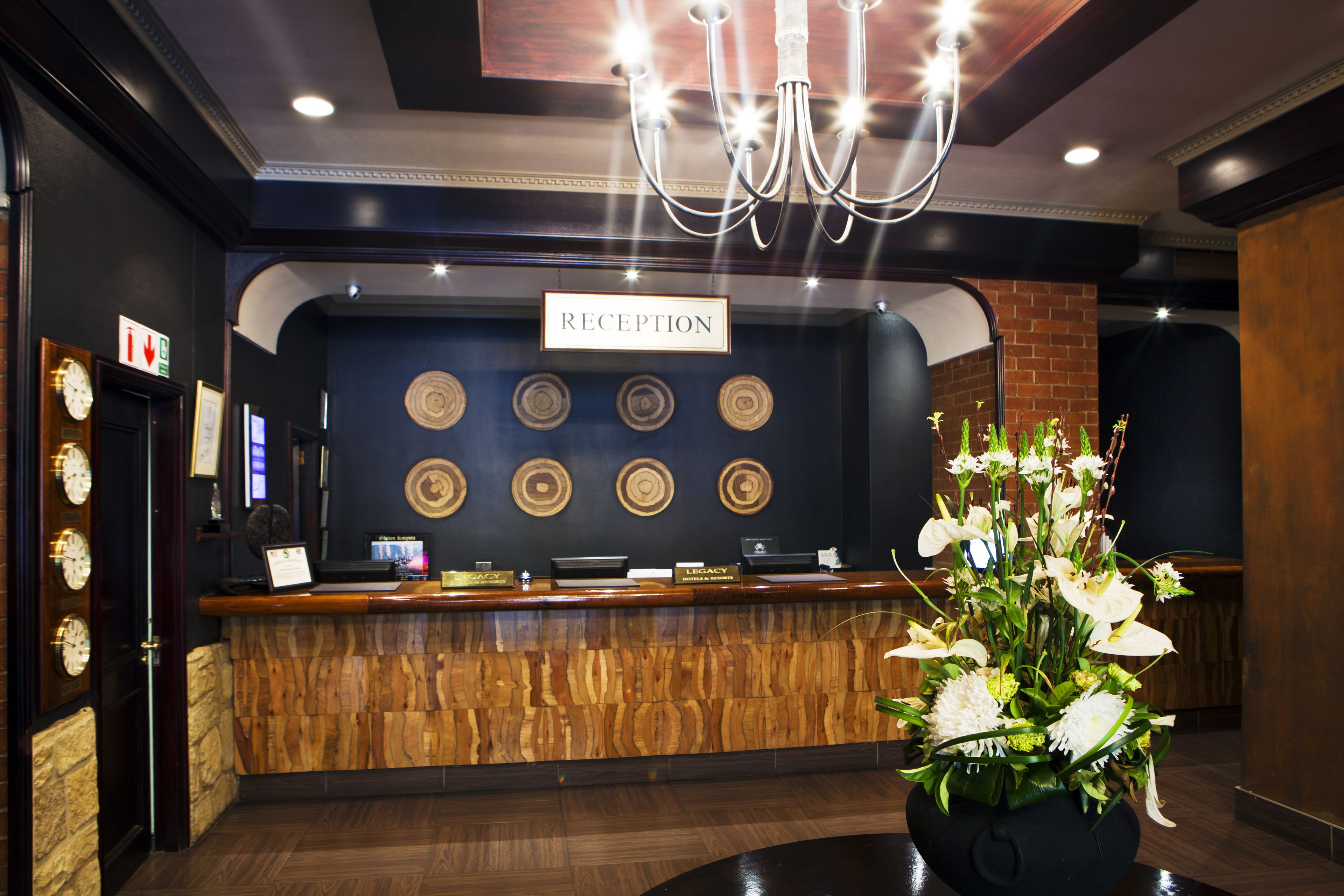 A reception area with a wooden reception desk, a chandelier, and a sign that reads "RECEPTION".