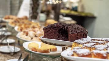 Una vitrina de panadería con diversos productos horneados, incluyendo un pastel de chocolate sobre un pedestal.
