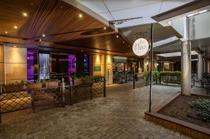An indoor courtyard with a café named 'Petit Paris,' featuring brick flooring, wooden ceiling, and potted plants. - Recanto Cataratas - Thermas, Resort e Convention (Foz do Iguaçu)