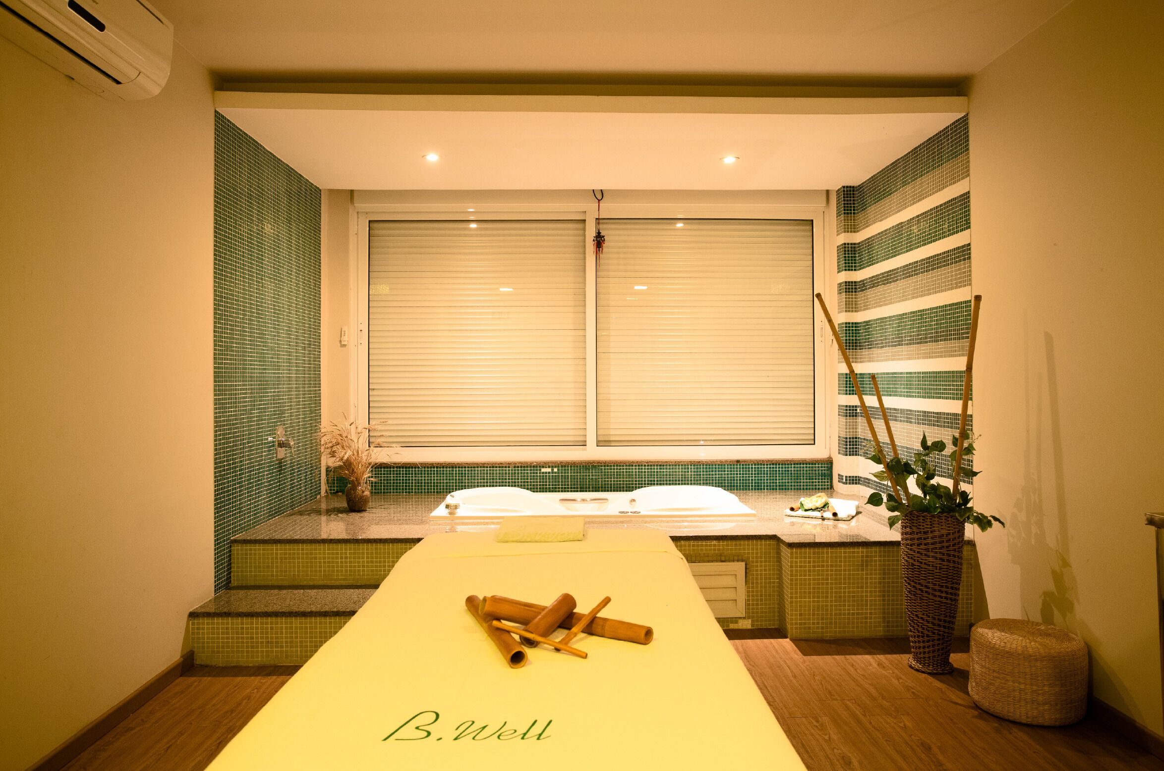 Una habitación con mostrador de recepción, una ventana con persianas, una planta y un taburete pequeño.
