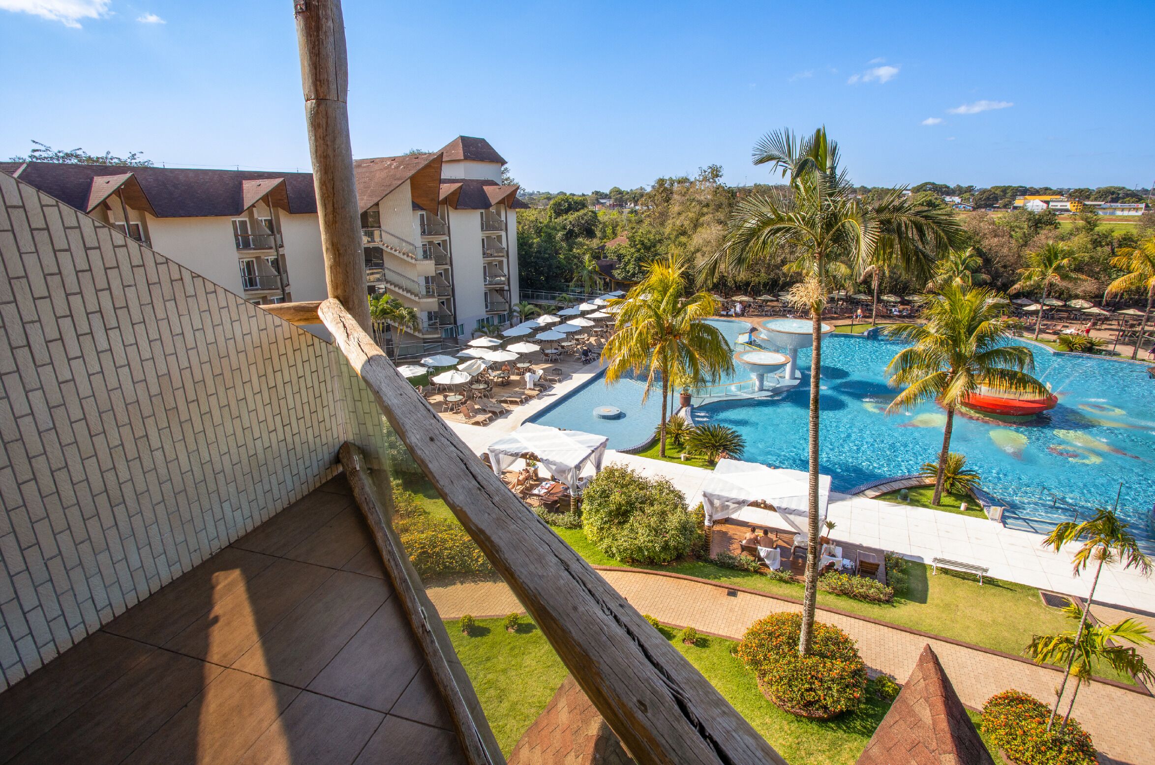 Un hotel con piscina, palmeras y vistas del paisaje circundante.