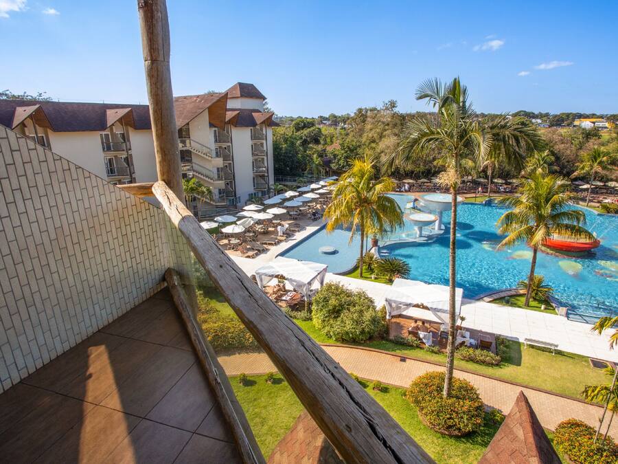 Et hotel med swimmingpool, palmer og udsigt over det omkringliggende landskab.