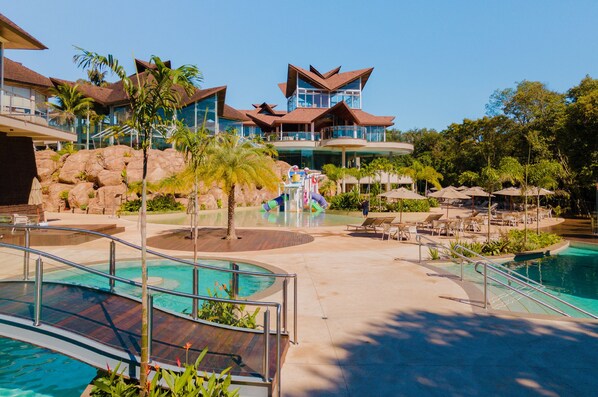 A resort with a pool, lounge chairs, and a water slide. - Recanto Cataratas - Thermas, Resort e Convention (Foz do Iguaçu)