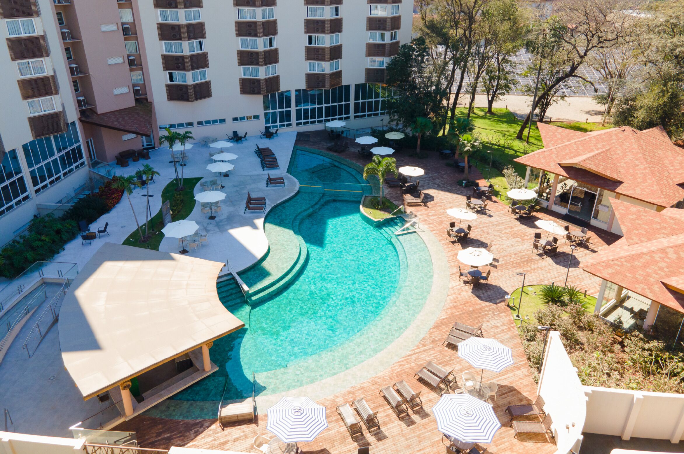 A hotel with a swimming pool, outdoor seating, and a covered area.