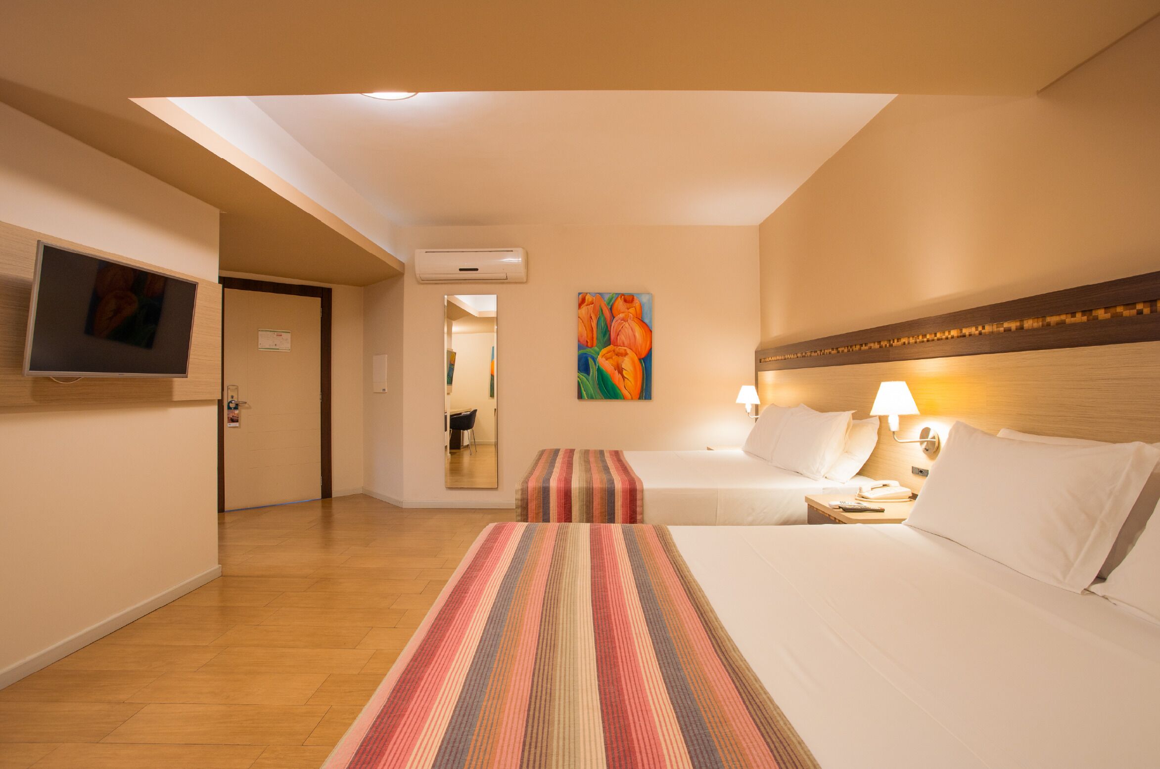 Ein Hotelzimmer mit zwei Betten, einem Fernseher, einem Gemälde und einer Lampe.