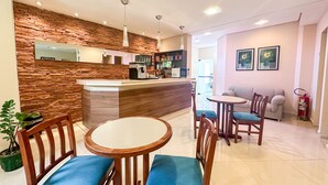 Una cucina moderna con rivestimento in pietra, una macchina da caffè e un forno a microonde. C'è un'area pranzo con sedie in legno e un piccolo tavolo rotondo.