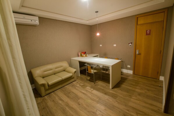 A room with a beige sofa, a white table, and a wooden door. - SJ Royal - San Juan Curitiba (Curitiba)