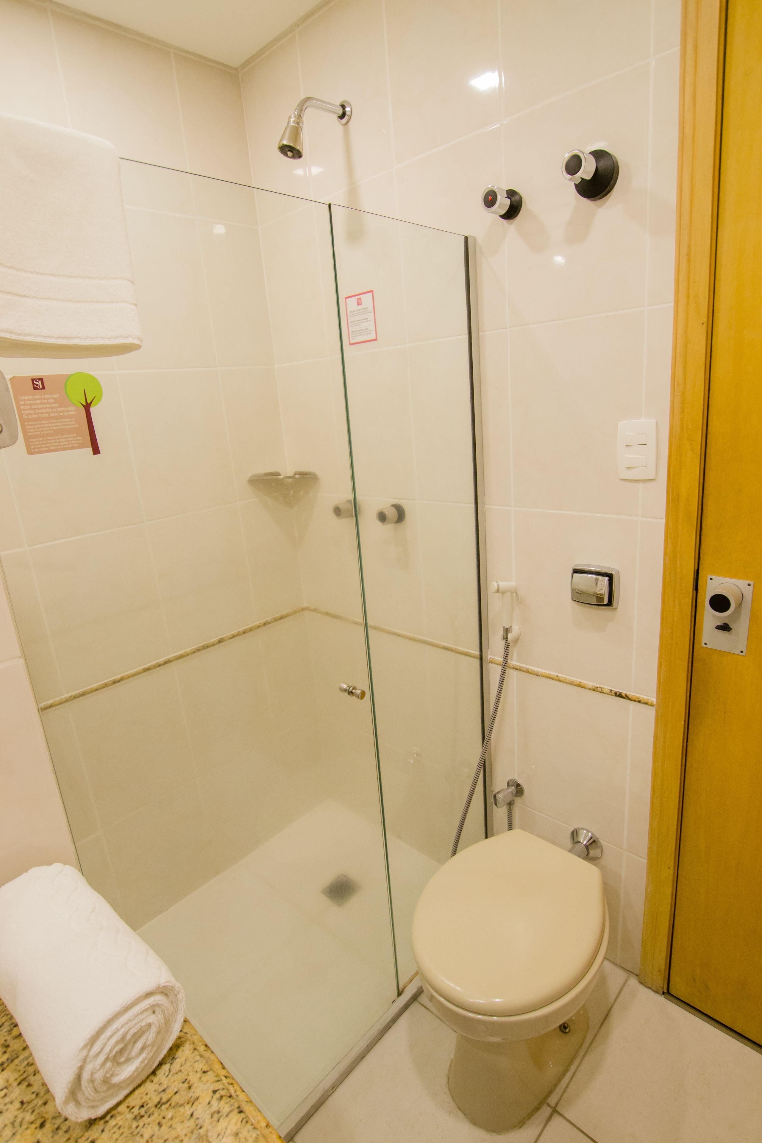 Un baño con ducha envuelta en vidrio, inodoro y una toalla sobre la encimera.