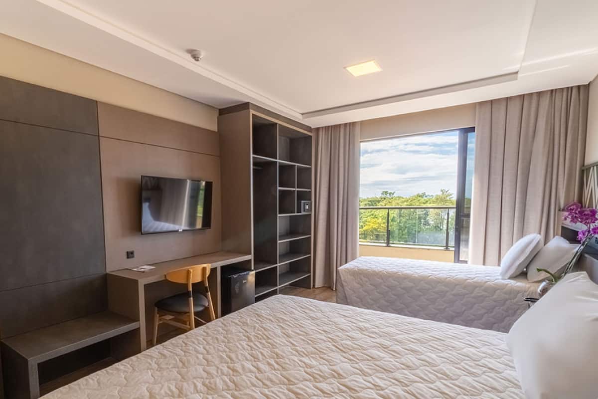 Une chambre d’hôtel avec deux lits, une télévision, un bureau et un balcon avec vue.