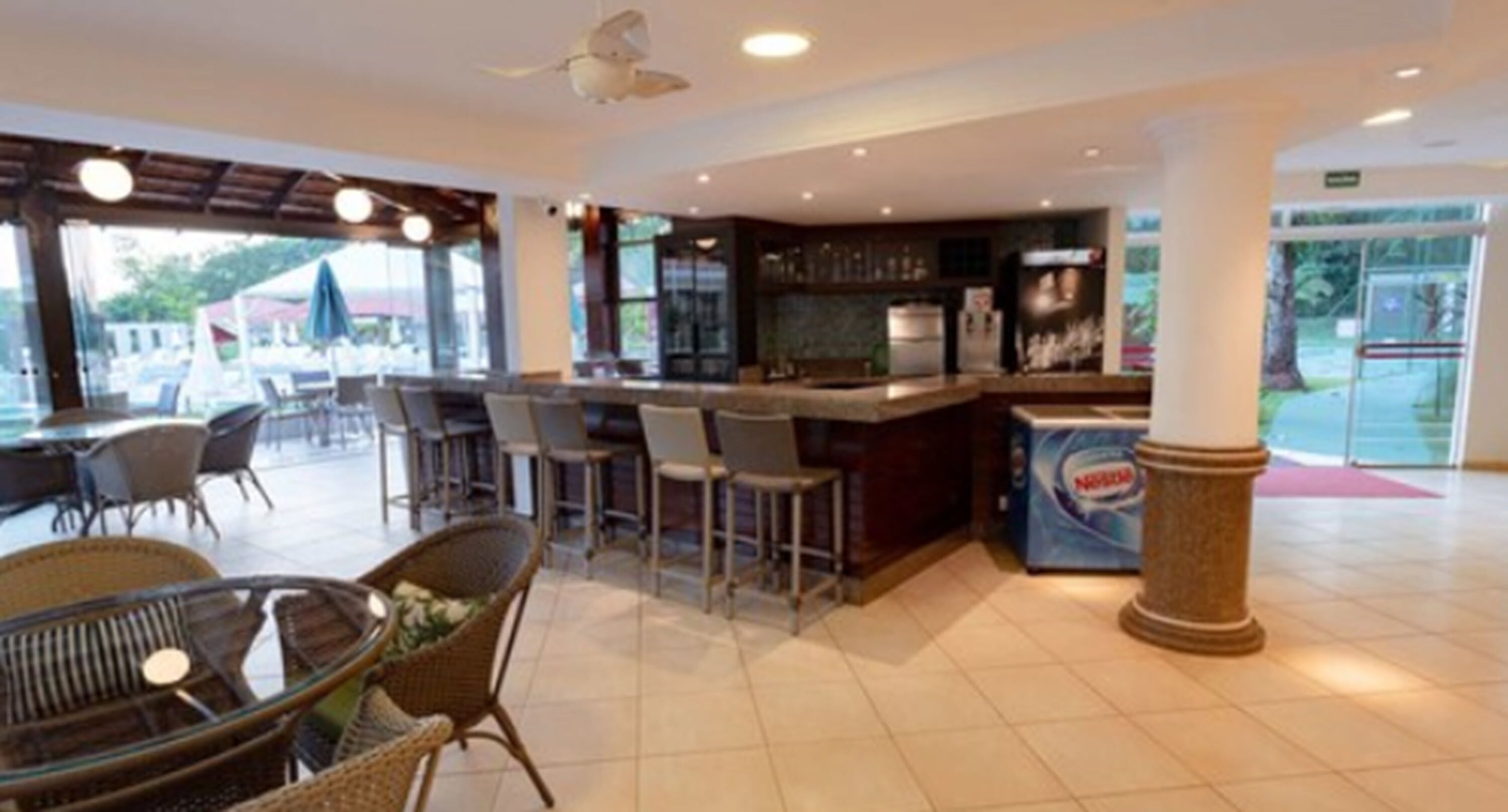 Amplo espaço interno com bar, assentos e vista para o exterior.
