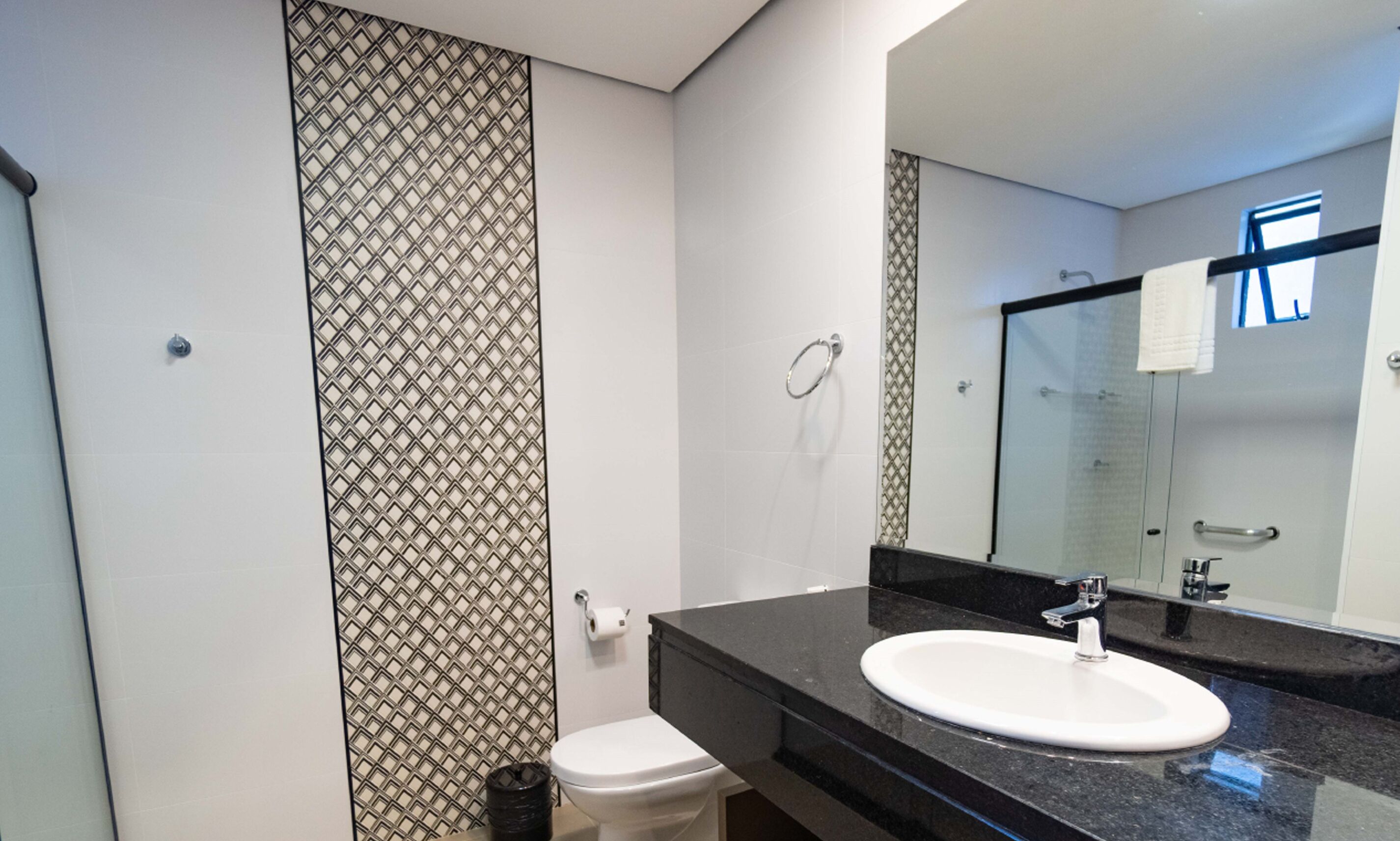 A modern bathroom with a black countertop sink, a toilet, and a shower area.