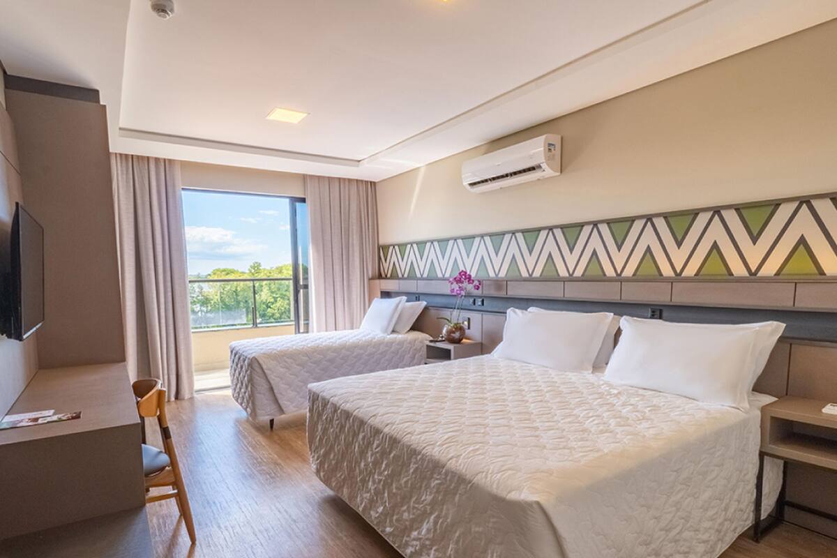 Une chambre d’hôtel avec deux lits, une télévision, un bureau et un balcon avec vue.