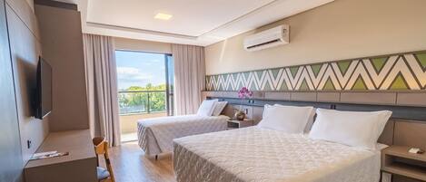 A hotel room with two beds, a TV, a desk, and a balcony with a view.