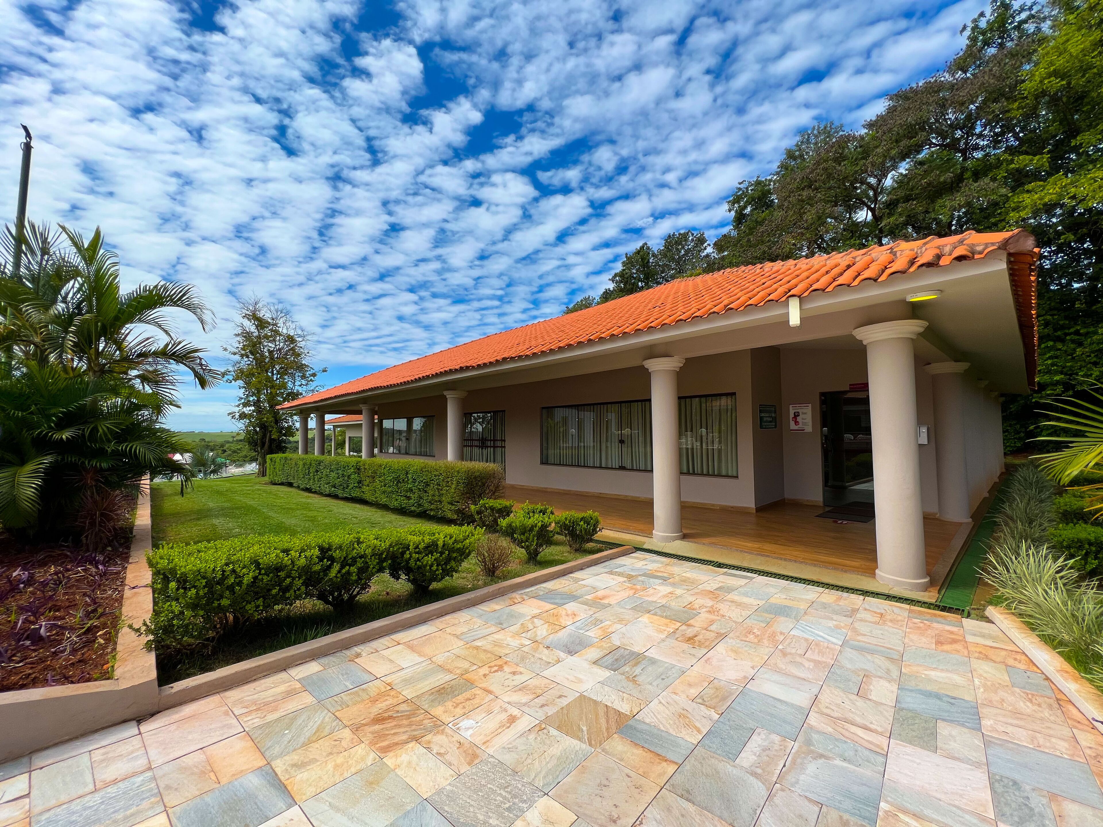 A modern building with a red-tiled roof, large windows, and a paved entrance area.