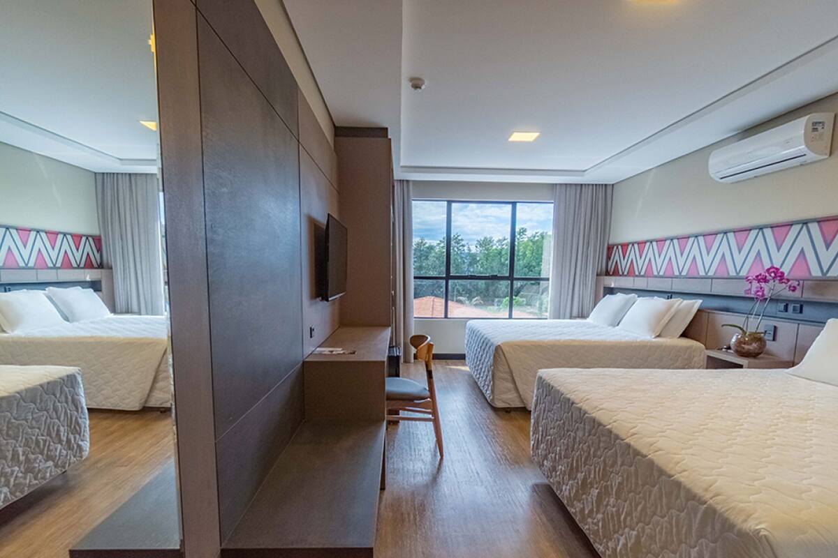 Une chambre d’hôtel avec deux lits, un bureau, une chaise, une télévision et une fenêtre donnant sur un beau paysage.