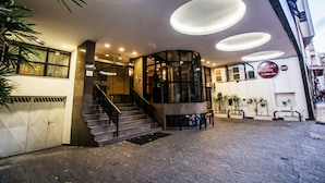 Entrada de un hotel con diseño moderno, que incluye una escalera, una recepción y un cartel que dice 'San Juan Hotels'.