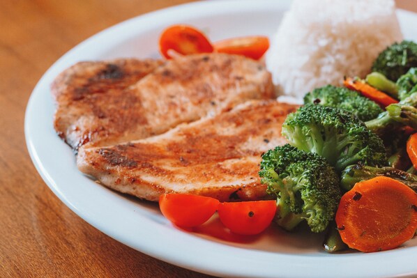 Un plato con carne a la parrilla, arroz y verduras.