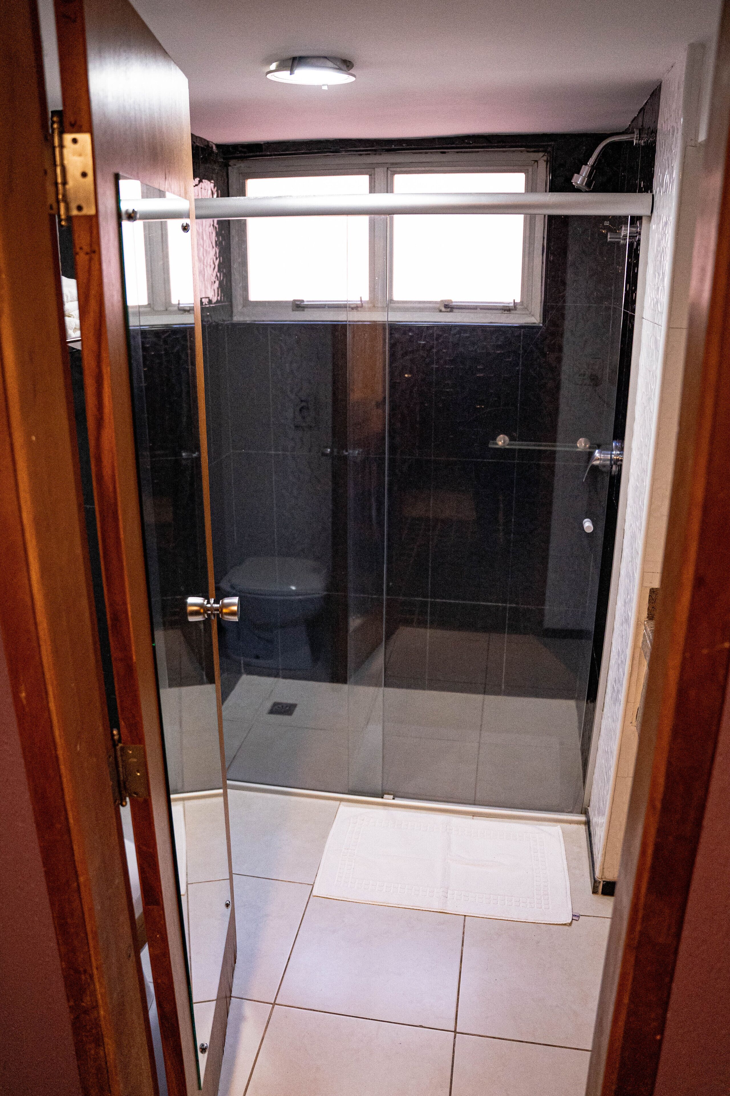 A glass-enclosed shower area with a toilet visible through the glass.
