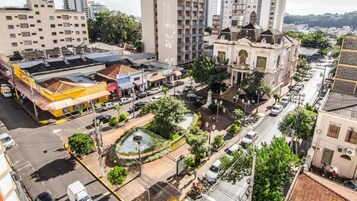 Un edificio de gran altura con una fuente en el centro, rodeado de vehículos estacionados y zonas verdes.