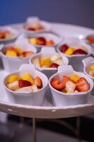Una serie de cuencos blancos con fruta sobre una bandeja blanca.
