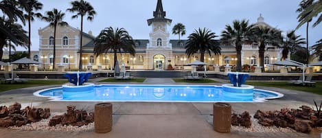 A large building with a prominent tower and a swimming pool in the foreground.