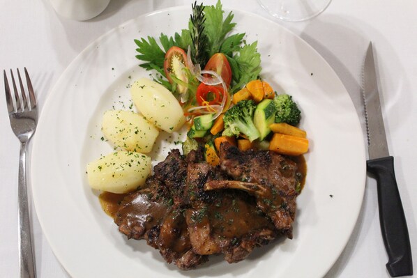 Un plato con carne, papas y verduras.