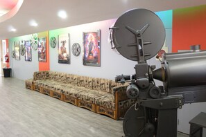 A room with a large projector, a sofa, and a wall with movie posters. - Swakopmund Hotel (Swakopmund)