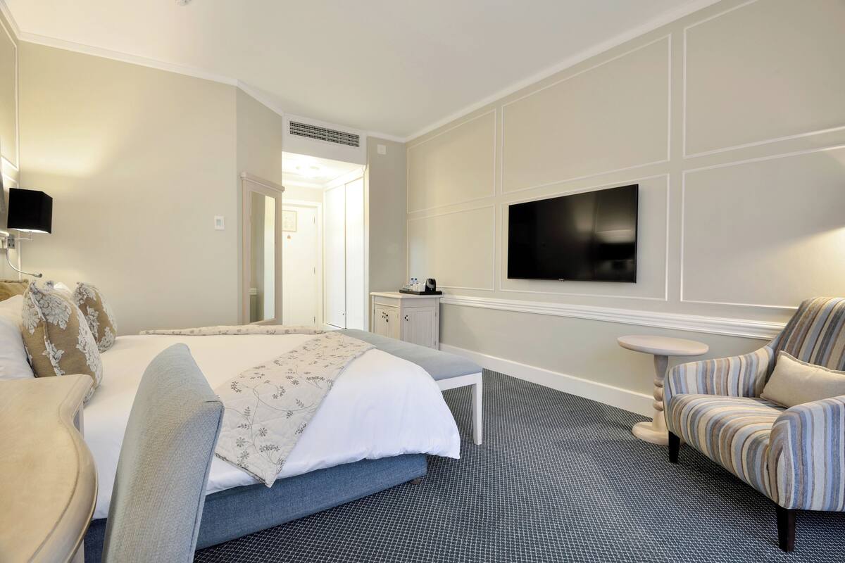 Une chambre d’hôtel avec un lit, un téléviseur fixé au mur, une petite table et une chaise.