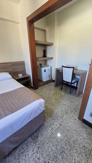 A hotel room with a bed, a desk, and a refrigerator. - Via Contorno Hotel (Belo Horizonte)