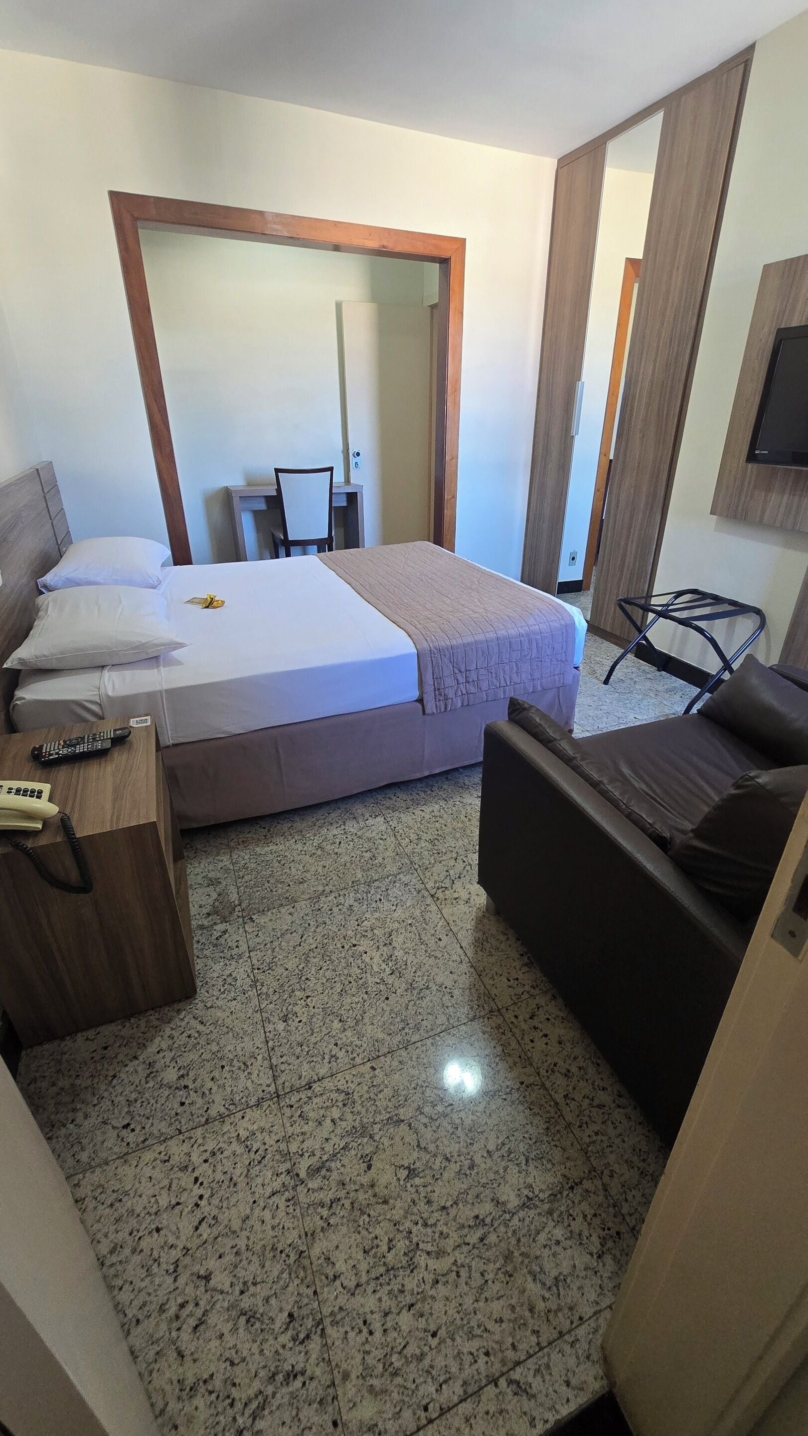 Een hotelkamer met een bed, een bureau, een stoel en een televisie.